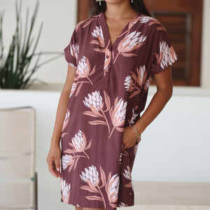 woman wearing a brown knee length v-neck dress with protea pattern