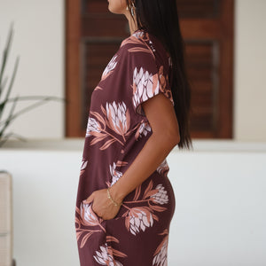 woman wearing a brown knee length v-neck dress with protea pattern