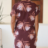 woman wearing a brown knee length v-neck dress with protea pattern