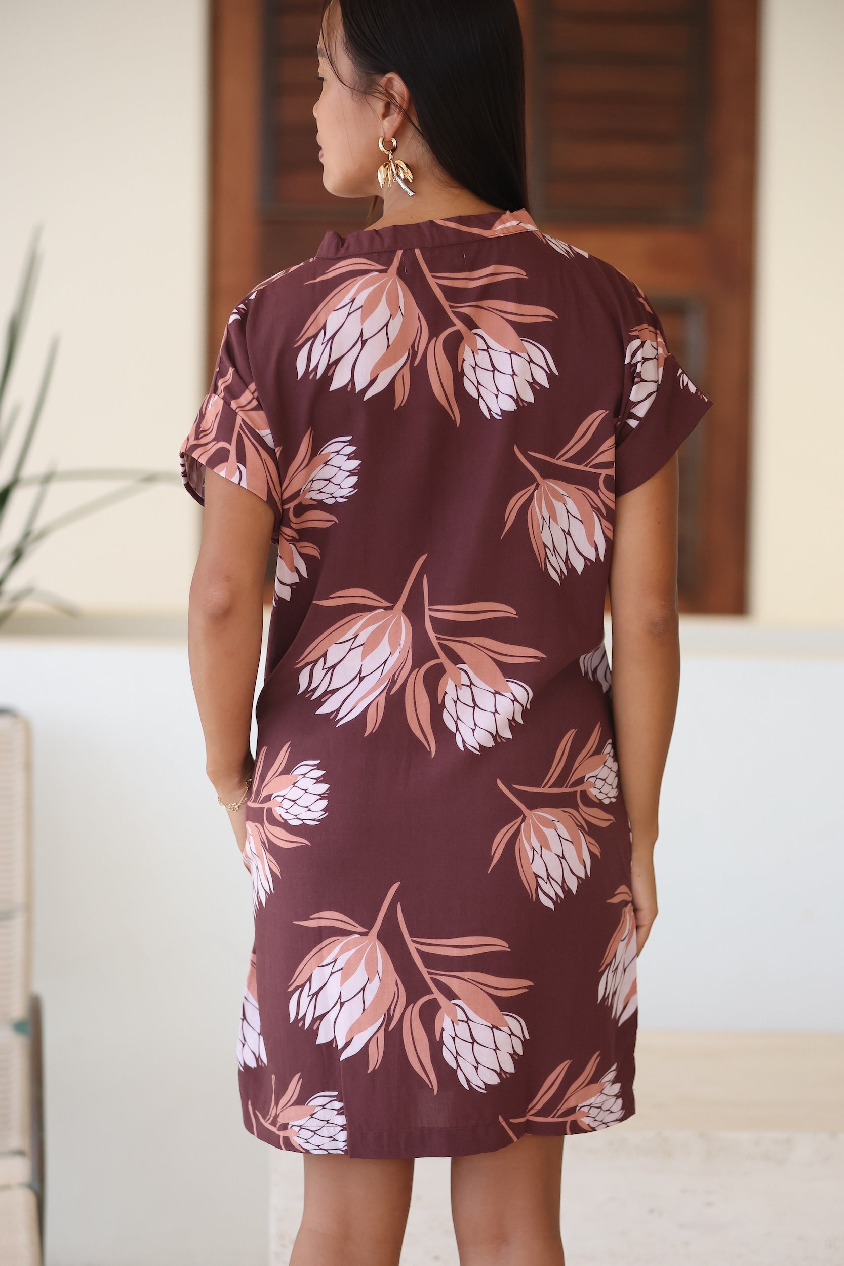 woman wearing a brown knee length v-neck dress with protea pattern