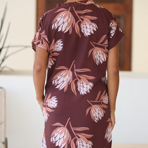 woman wearing a brown knee length v-neck dress with protea pattern