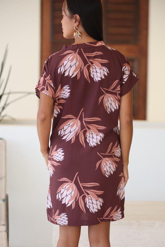 woman wearing a brown knee length v-neck dress with protea pattern