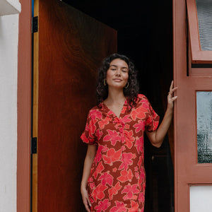 woman with brown hair wearing a half button v neck dress with retro pink pua print