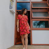 woman with brown hair wearing a half button v neck dress with retro pink pua print