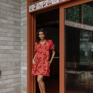 woman with brown hair wearing a half button v neck dress with retro pink pua print