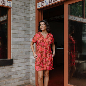 woman with brown hair wearing a half button v neck dress with retro pink pua print