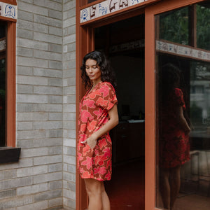 woman with brown hair wearing a half button v neck dress with retro pink pua print