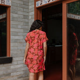 woman with brown hair wearing a half button v neck dress with retro pink pua print
