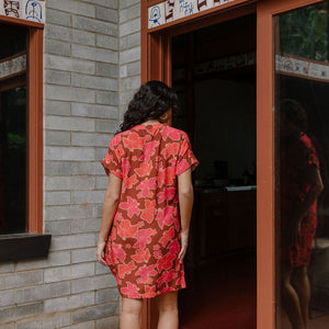 woman with brown hair wearing a half button v neck dress with retro pink pua print