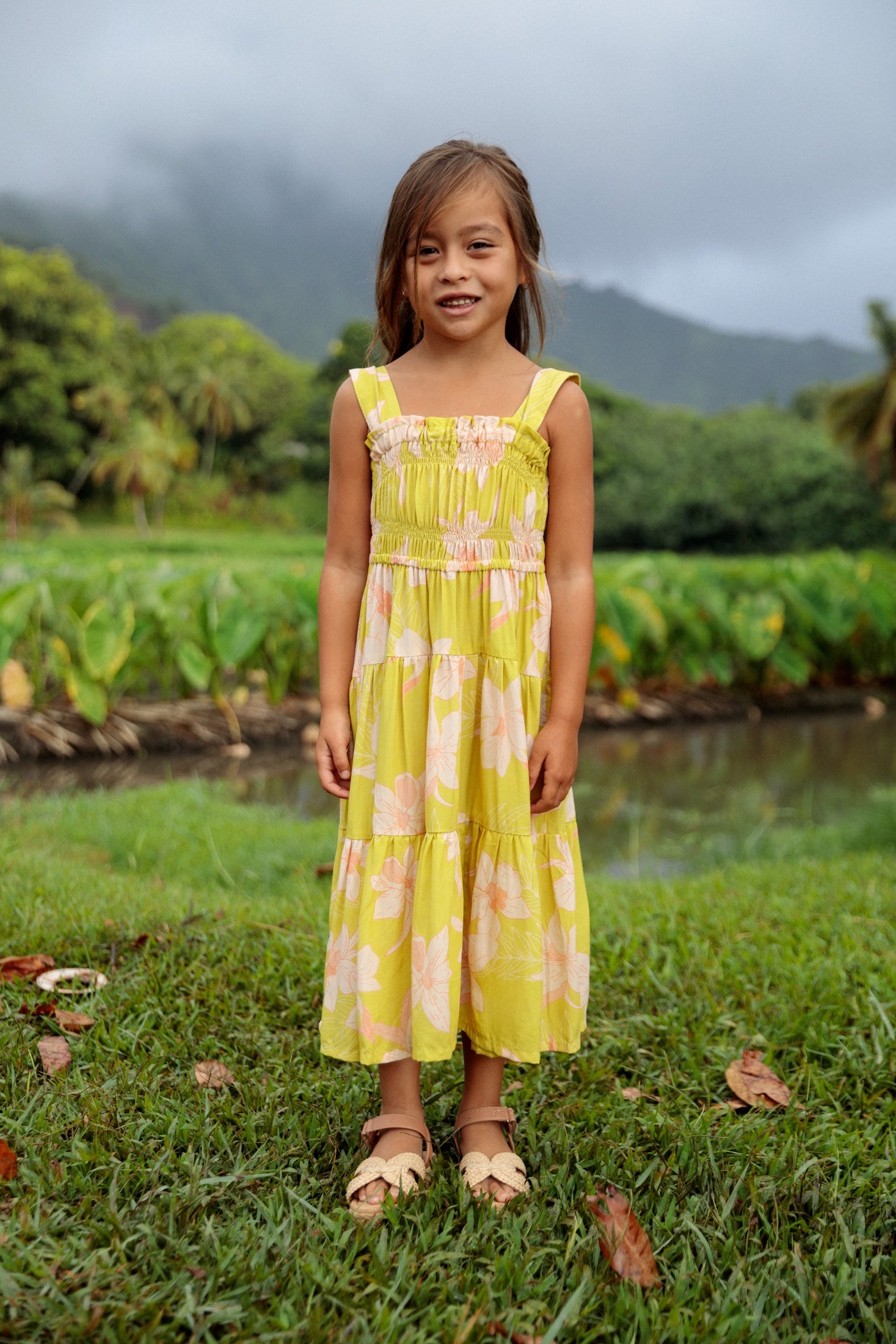 little girl wearing long flowy dress in bright green with orchid pattern