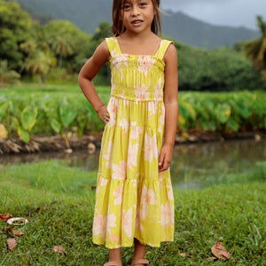 little girl wearing long flowy dress in bright green with orchid pattern