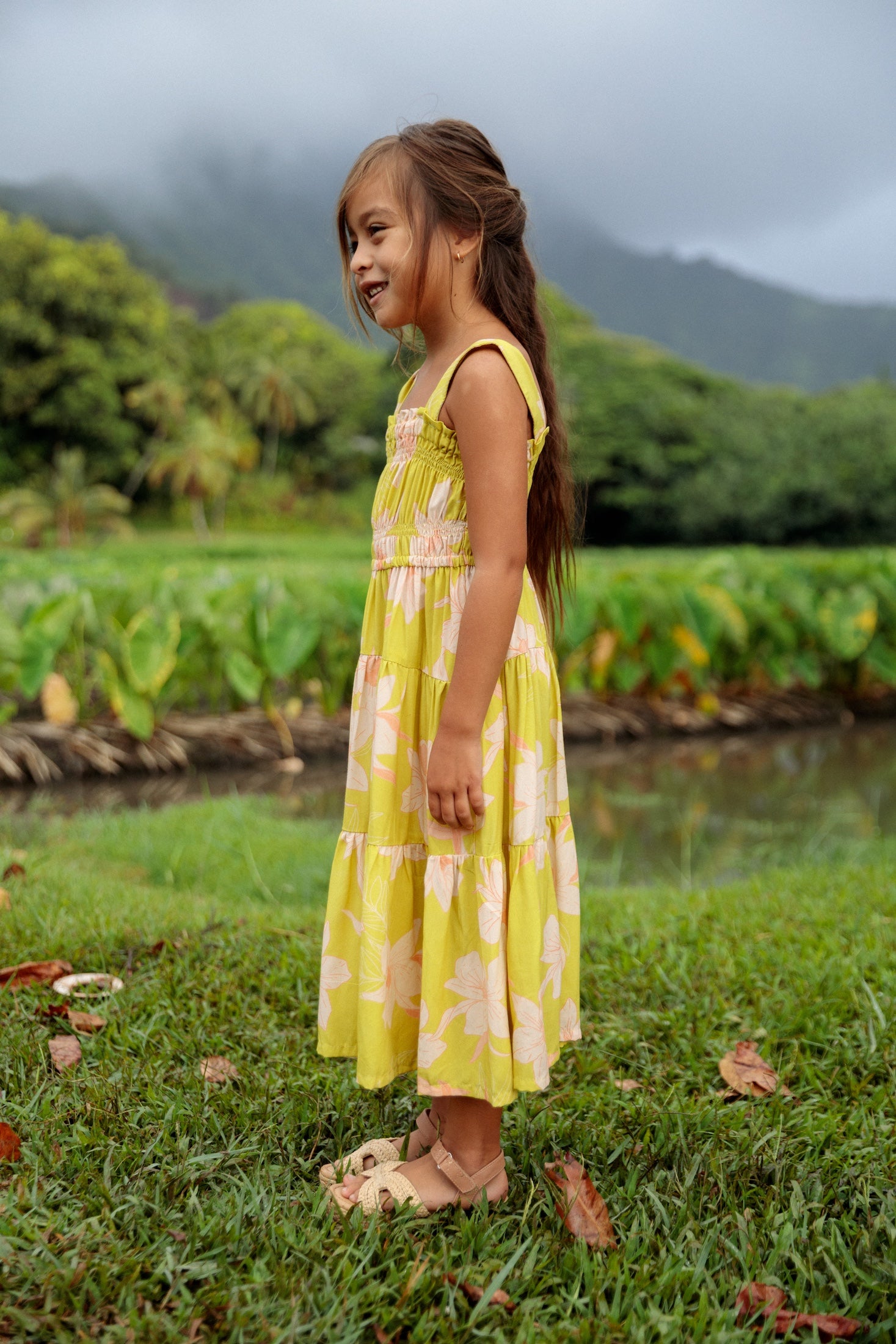 little girl wearing long flowy dress in bright green with orchid pattern