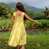little girl wearing long flowy dress in bright green with orchid pattern