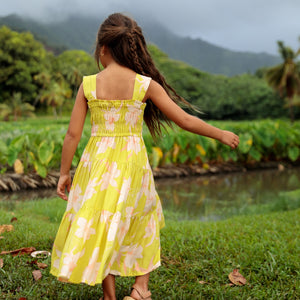 little girl wearing long flowy dress in bright green with orchid pattern