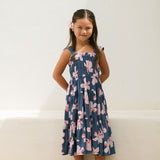 little girl wearing a tiered maxi dress in navy and pink hibiscus print.