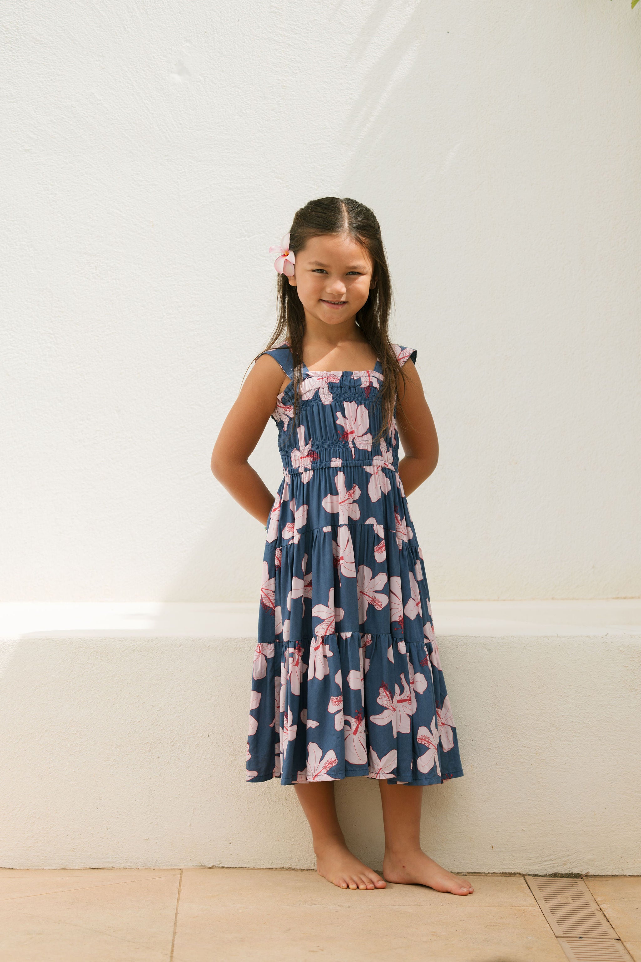 little girl wearing a tiered maxi dress in navy and pink hibiscus print.