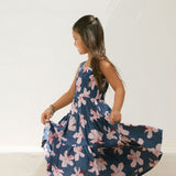 little girl wearing a tiered maxi dress in navy and pink hibiscus print.