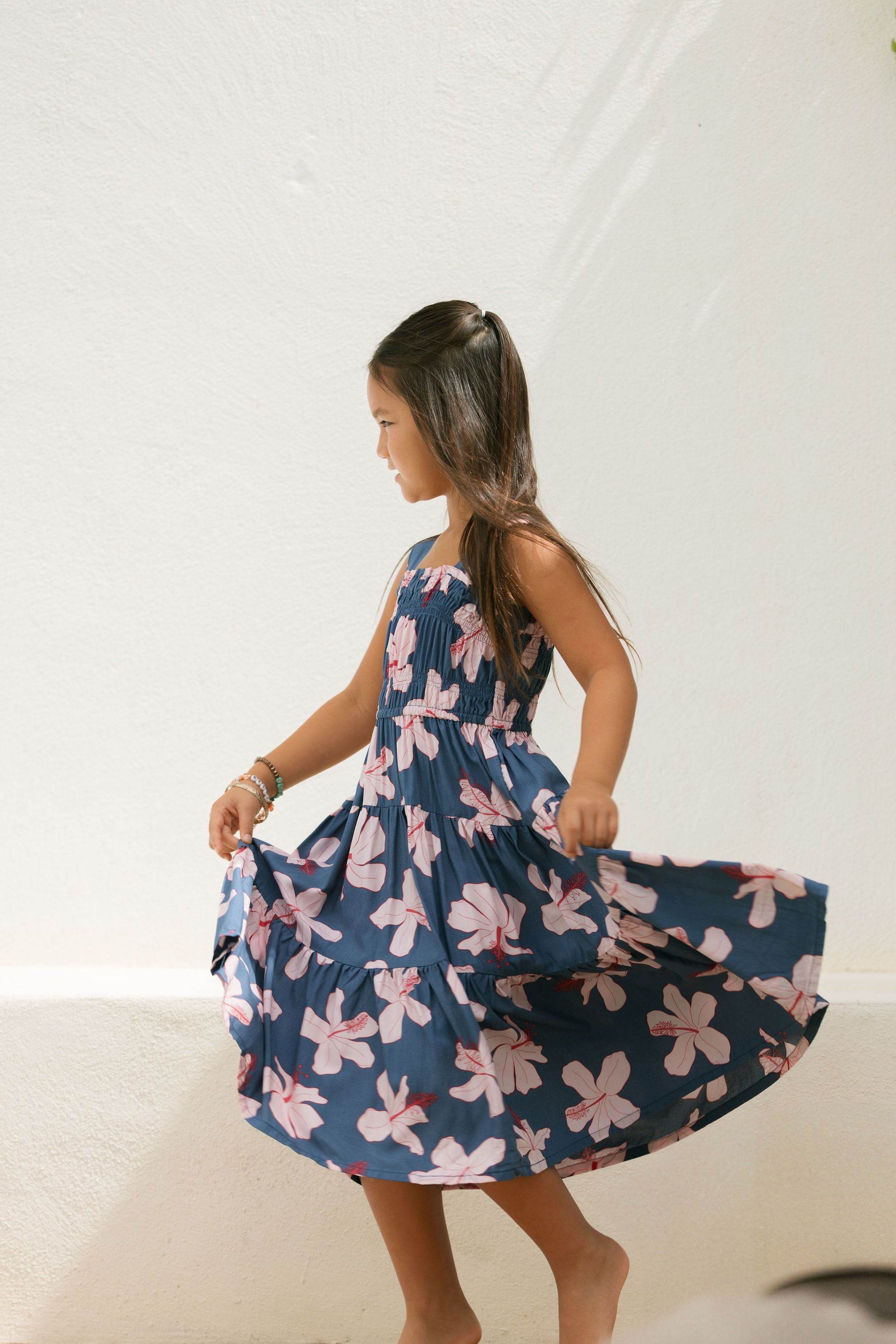 little girl wearing a tiered maxi dress in navy and pink hibiscus print.
