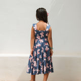 little girl wearing a tiered maxi dress in navy and pink hibiscus print.
