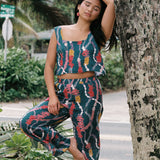 woman with brown hair wearing a matching top and pant set in dark teal with shell and lei print