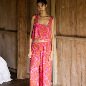 A woman with dark hair wears a YIREH flowy cropped top. It is the Naia Top in the Garden 'Awapuhi print. 