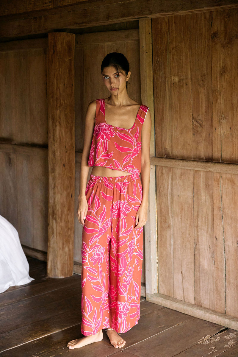 A woman with dark hair wears a YIREH wide legged pant with elastic waistband. It is the Elodi Pant in the Garden 'Awapuhi print. 