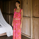 A woman with dark hair wears a YIREH flowy cropped top. It is the Naia Top in the Garden 'Awapuhi print. 