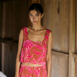 A woman with dark hair wears a YIREH flowy cropped top. It is the Naia Top in the Garden 'Awapuhi print. 