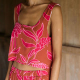 A woman with dark hair wears a YIREH flowy cropped top. It is the Naia Top in the Garden 'Awapuhi print. 
