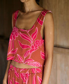 A woman with dark hair wears a YIREH flowy cropped top. It is the Naia Top in the Garden 'Awapuhi print. 