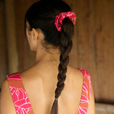 A woman with dark hair wears a YIREH flowy cropped top. It is the Naia Top in the Garden 'Awapuhi print. 