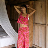 A woman with dark hair wears a YIREH flowy cropped top. It is the Naia Top in the Garden 'Awapuhi print. 