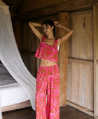 A woman with dark hair wears a YIREH flowy cropped top. It is the Naia Top in the Garden 'Awapuhi print. 