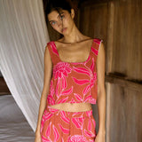 A woman with dark hair wears a YIREH flowy cropped top. It is the Naia Top in the Garden 'Awapuhi print. 