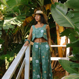 woman wearing lush green long flowy pants with puakenikeni