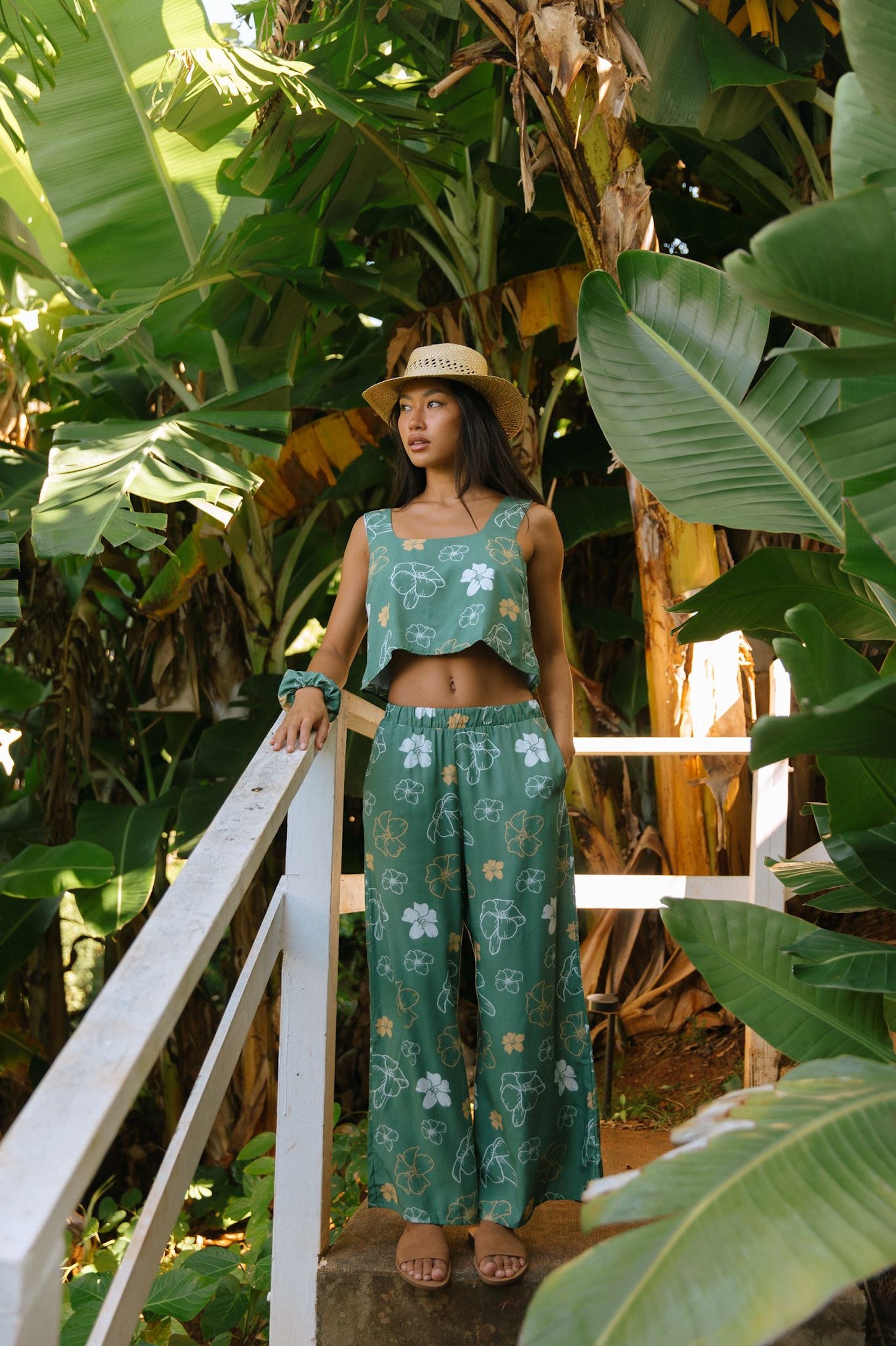 woman wearing lush green long flowy pants with puakenikeni