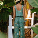 woman wearing lush green long flowy pants with puakenikeni