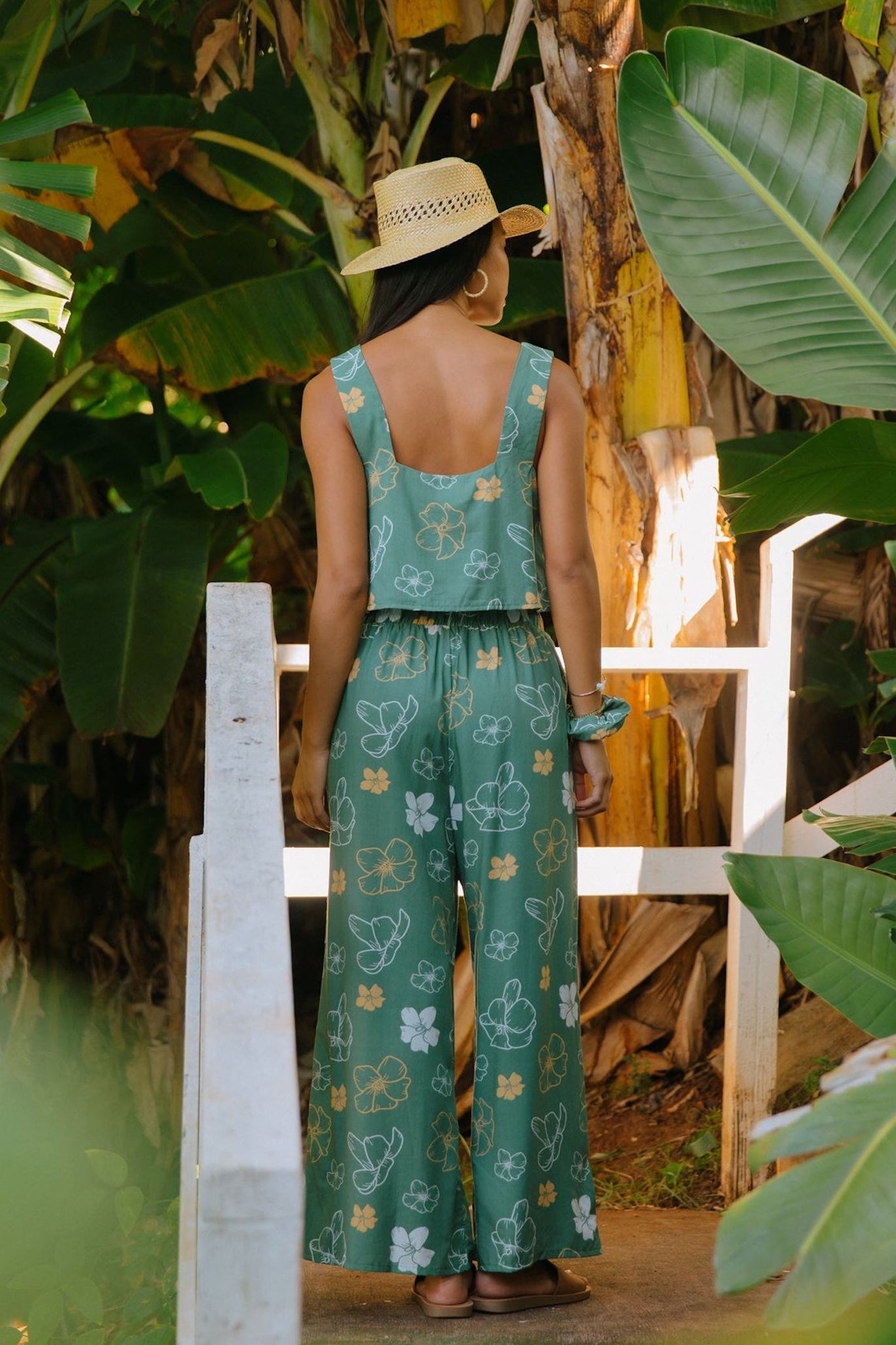 woman wearing lush green long flowy pants with puakenikeni