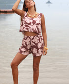 Woman with brown hair wearing a matching top and shorts set  in blush and brown hibiscus print. It is the Naia Top and Millie Shorts.