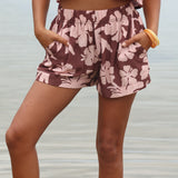 Woman with brown hair wearing a matching top and shorts set  in blush and brown hibiscus print. It is the Naia Top and Millie Shorts.