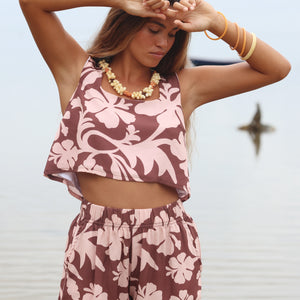Woman with brown hair wearing a matching top and shorts set  in blush and brown hibiscus print. It is the Naia Top and Millie Shorts.