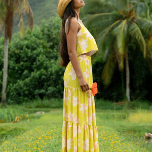 woman wearing a bright green orchid print cropped top with matching maxi skirt
