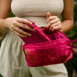 woman holding an expandable neoprene travel pouch with palaka and kokio print