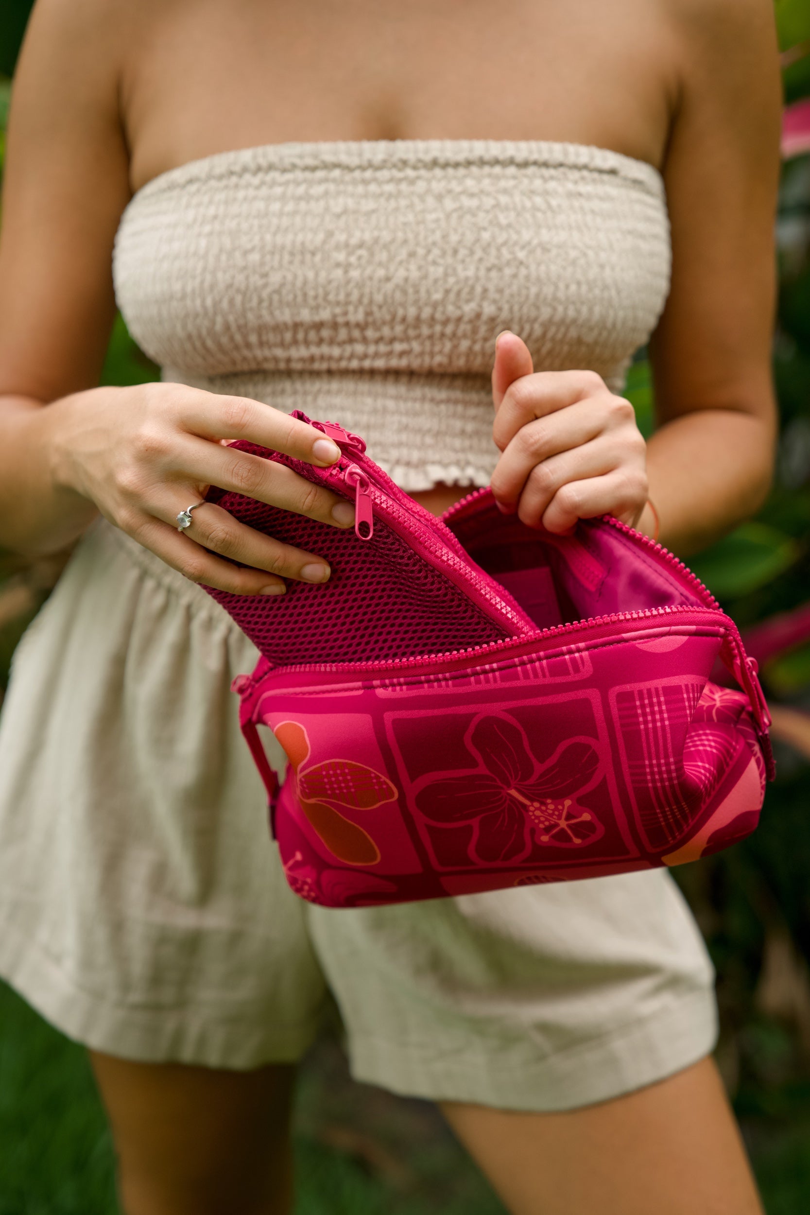 woman holding an expandable neoprene travel pouch with palaka and kokio print