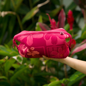woman holding an expandable neoprene travel pouch with palaka and kokio print