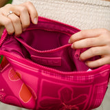 woman holding an expandable neoprene travel pouch with palaka and kokio print