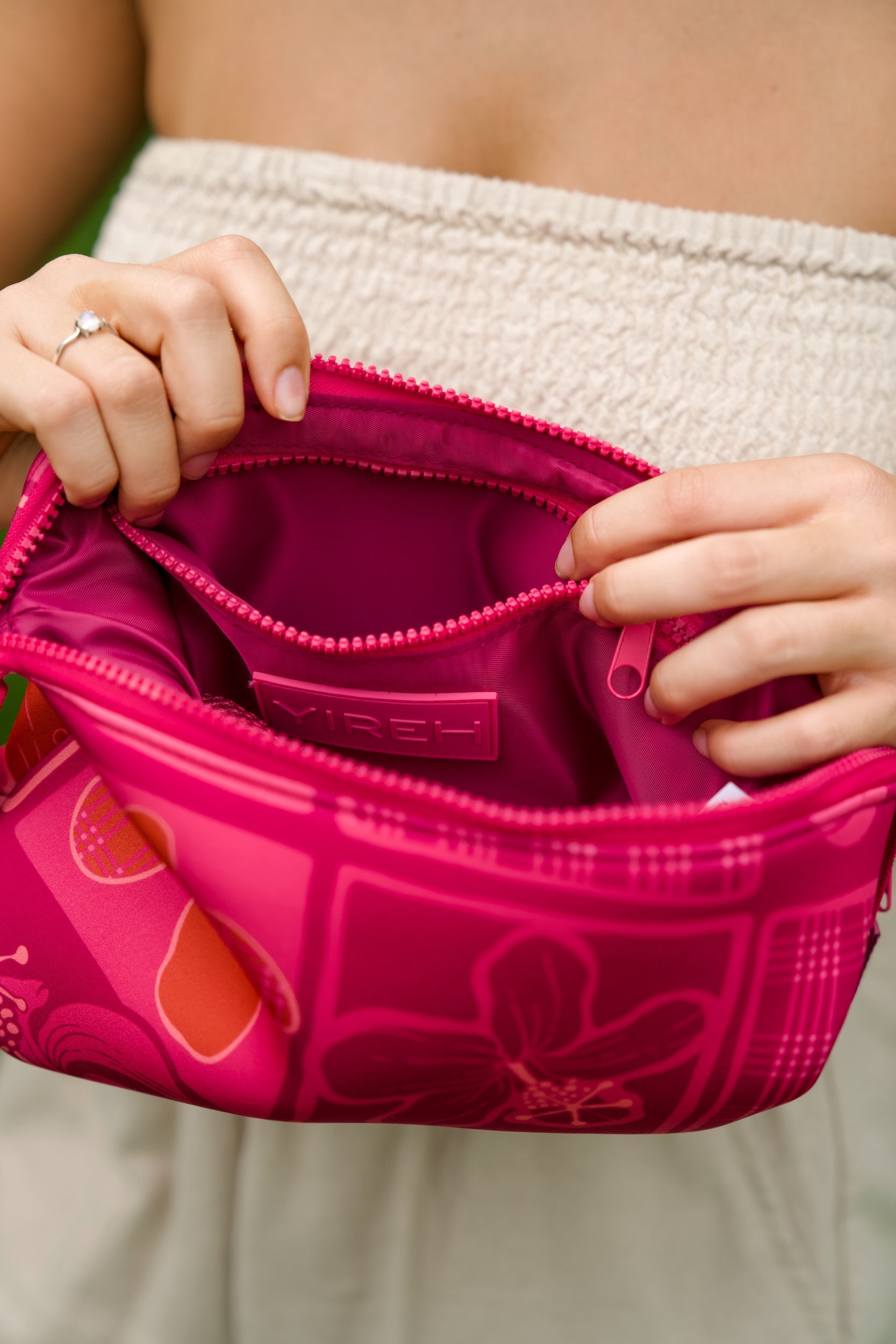 woman holding an expandable neoprene travel pouch with palaka and kokio print