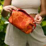 woman holding expandable puakenikeni printed neoprene pouch with detachable mini pouches