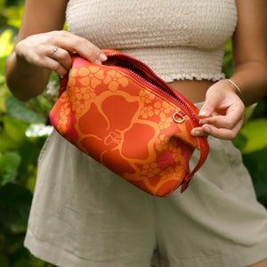 woman holding expandable puakenikeni printed neoprene pouch with detachable mini pouches
