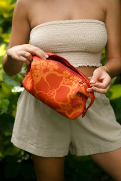 woman holding expandable puakenikeni printed neoprene pouch with detachable mini pouches